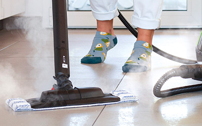 La photo montre une personne nettoyant le sol à la vapeur